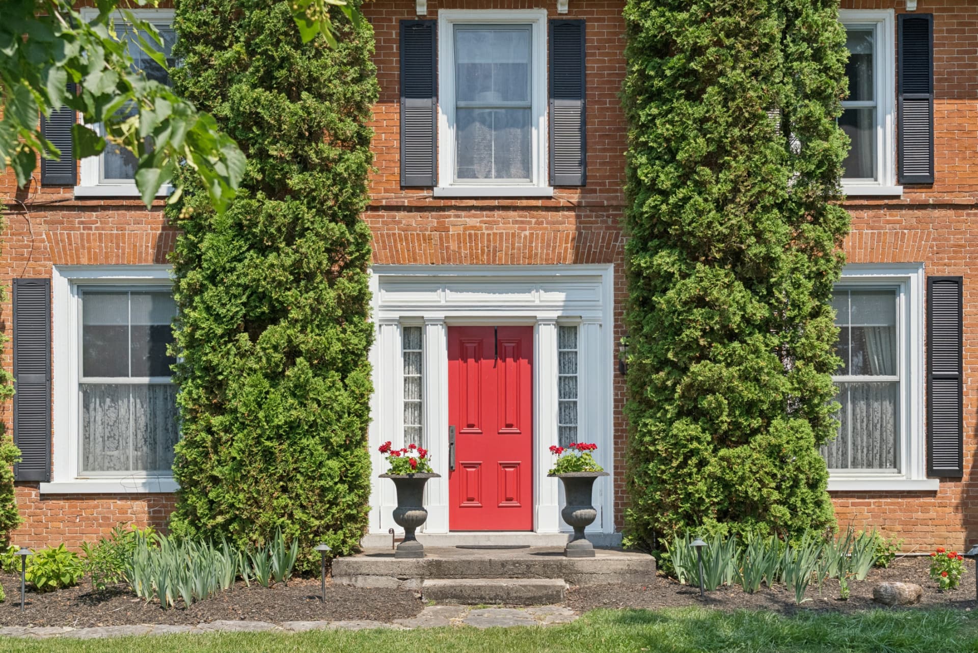 Red front door and brick facade of the 1847 farmhouse at McBain Farm