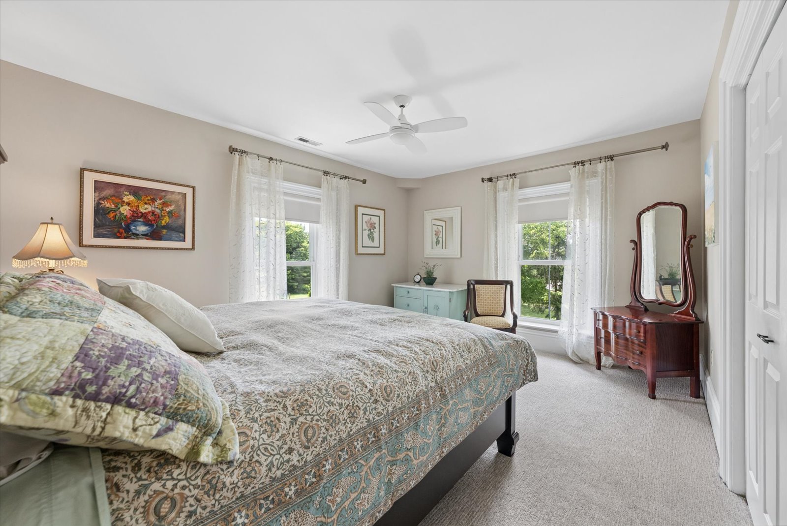 Guest bedroom with pair of windows and antique dressing mirror