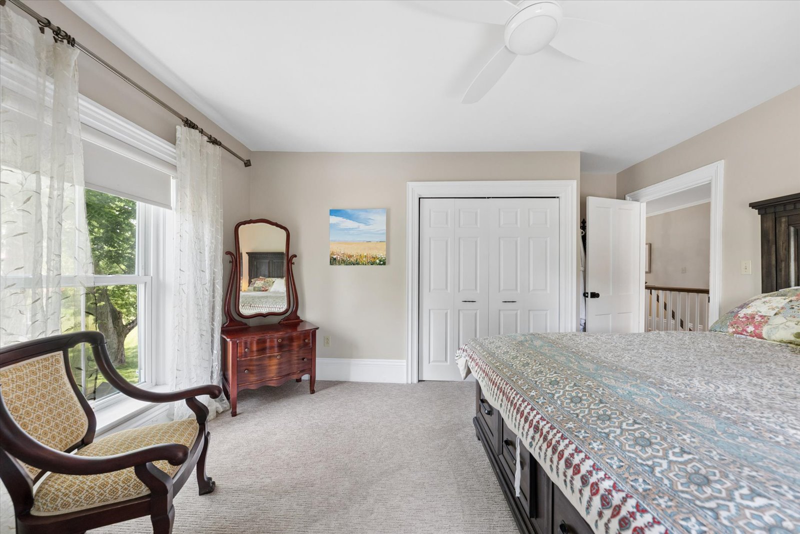 Guest bedroom with antique dresser mirror and garden views