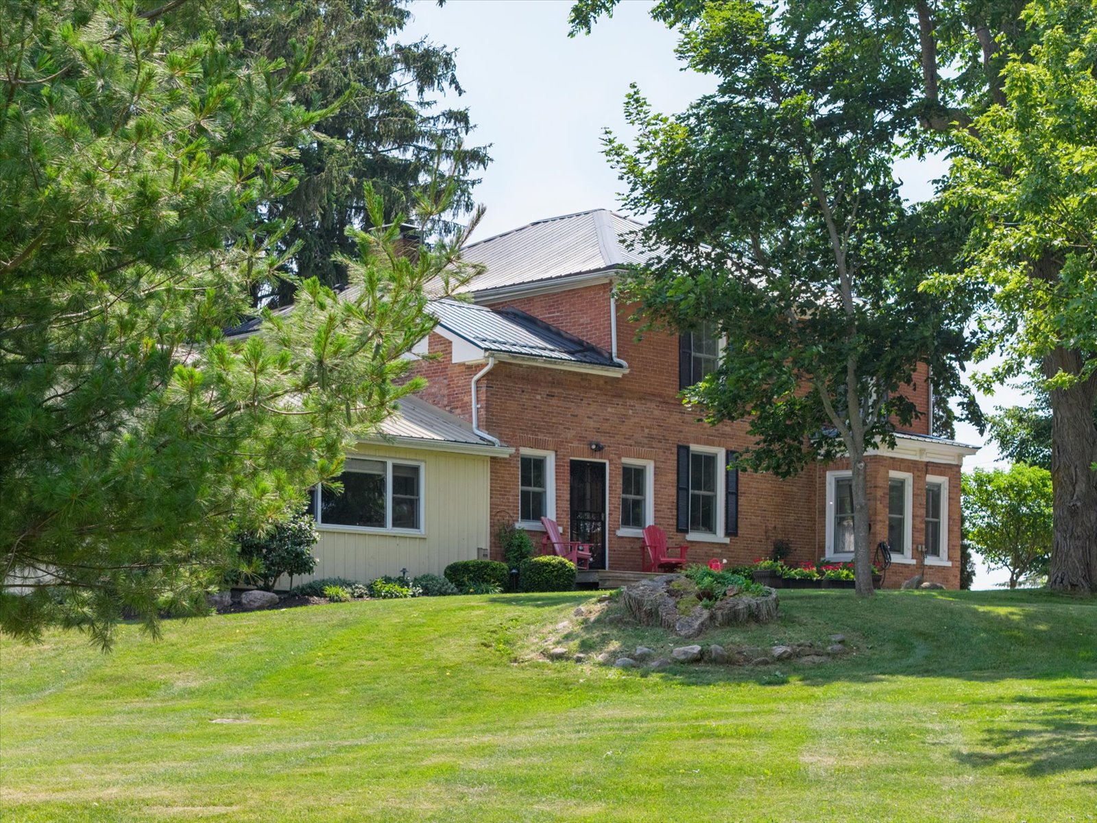 Farmhouse framed by mature pines and maples
