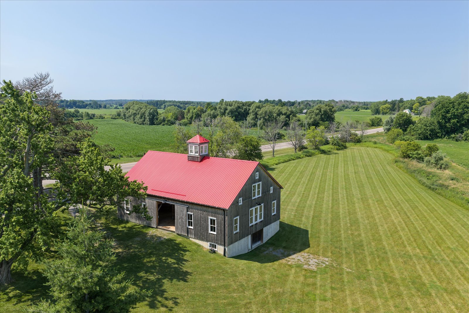 Aerial view of the barn's red roof, cupola and mown field