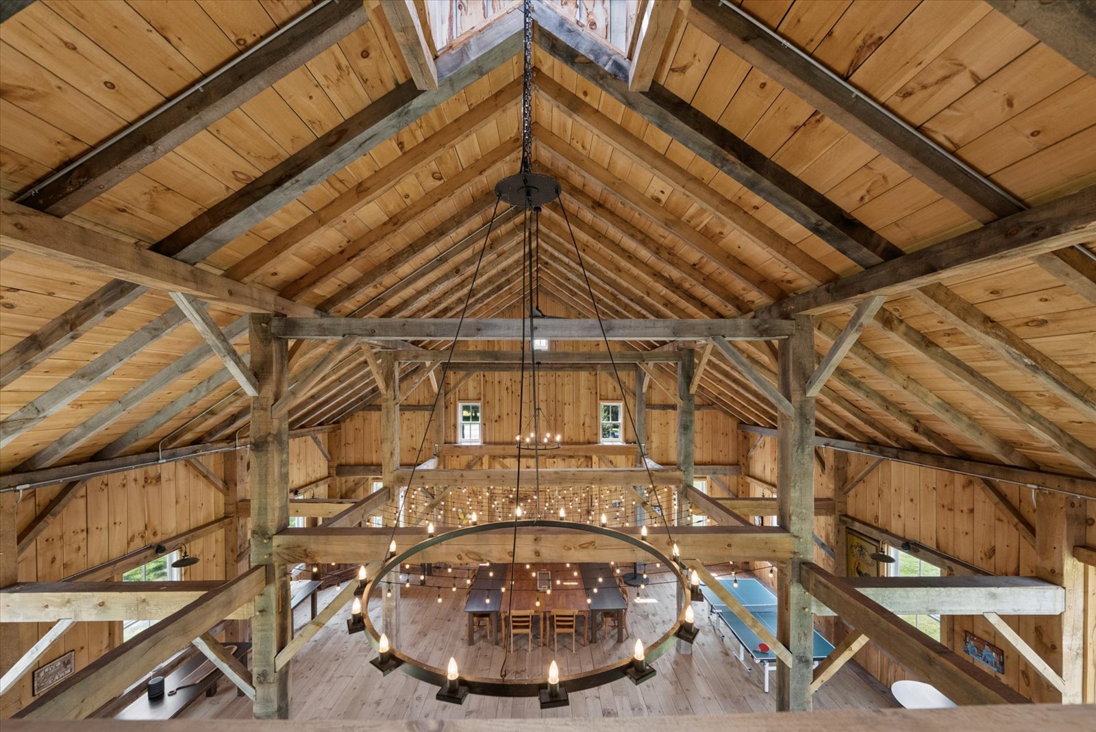 Loft view of the barn's timber trusses and ring chandelier